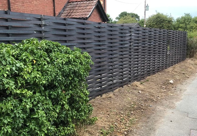 Completed metal woven fence behind bush