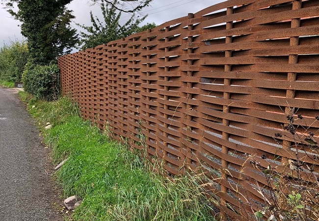 Completed, aged metal woven fence on top of grass