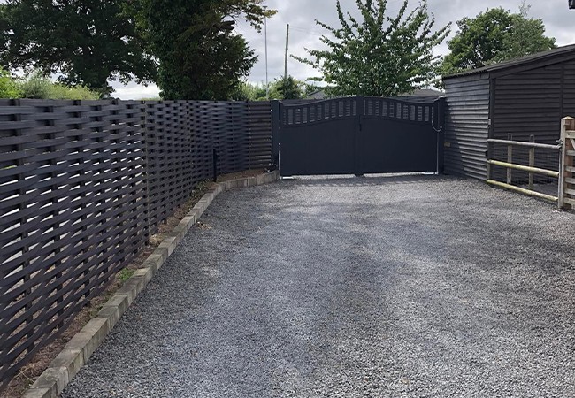 Completed black woven fence connected to a tall wooden gate.