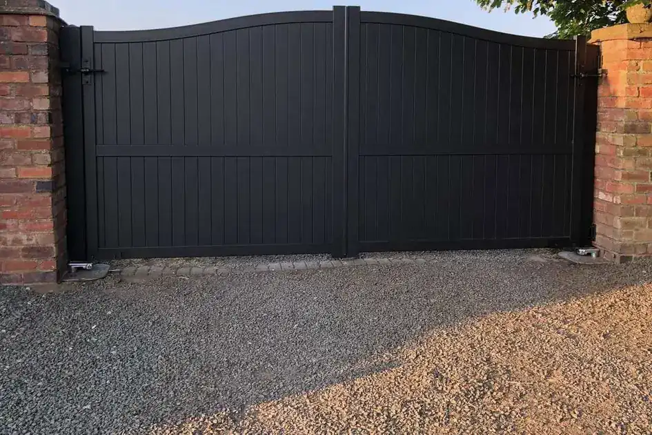 Anthracite solid-panel gates with an arched top between brick piers
