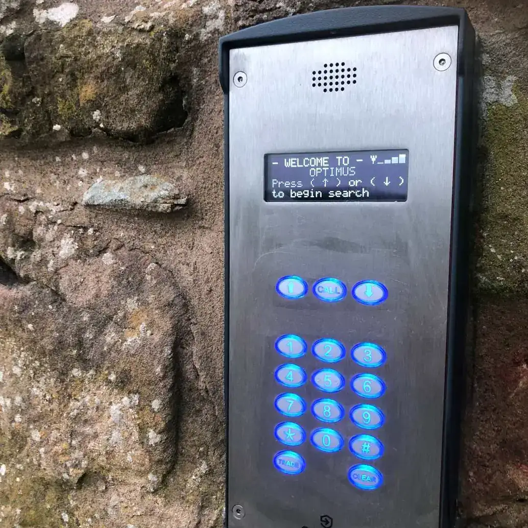 Intercom with a keypad and display mounted on a stone wall