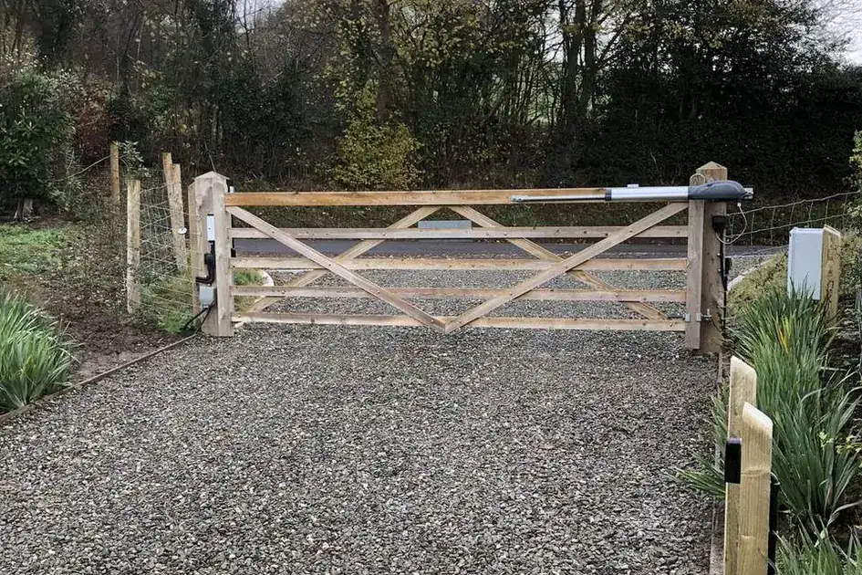 Timber five-bar gate across a gravel track, trees behind