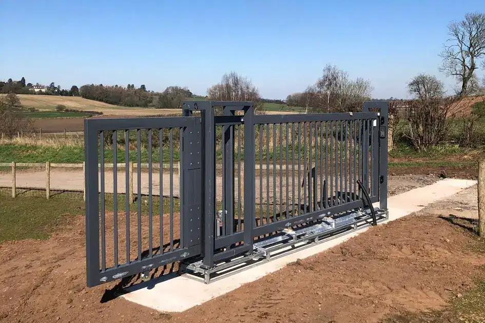 Steel sliding gate on a new concrete track at a farm entrance, fields behind