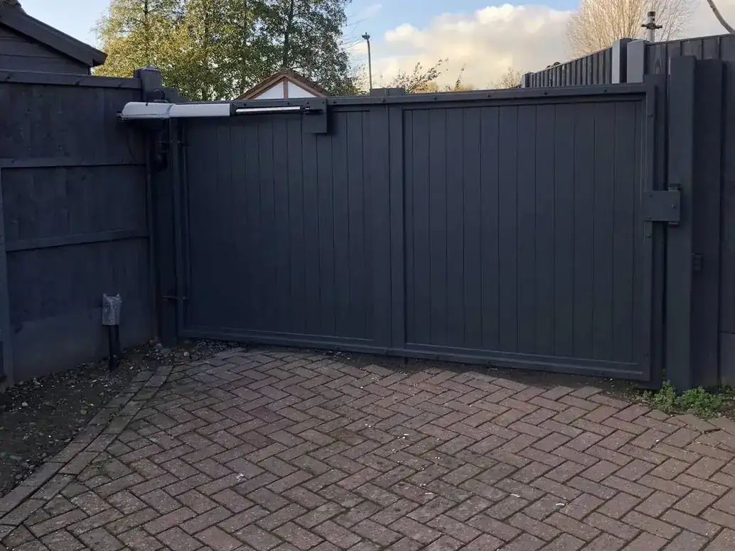Dark grey solid-panel gates and matching fence panels on a block-paved drive