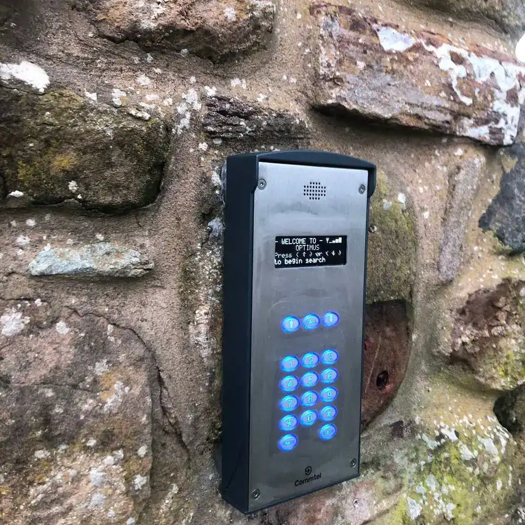 Intercom with a keypad and display mounted on a stone wall