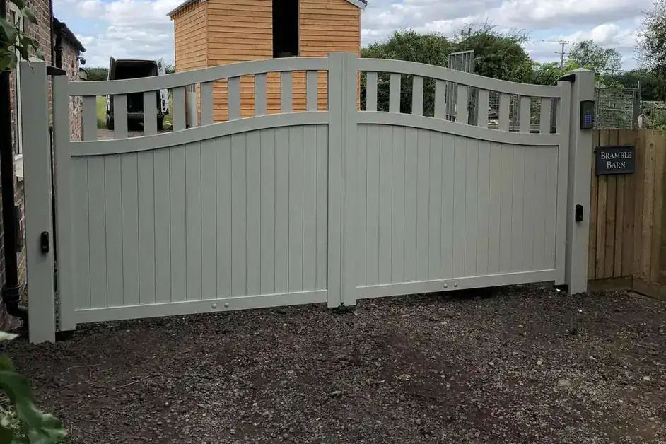 Sage green solid-panel driveway gates in front of a timber-clad outbuilding