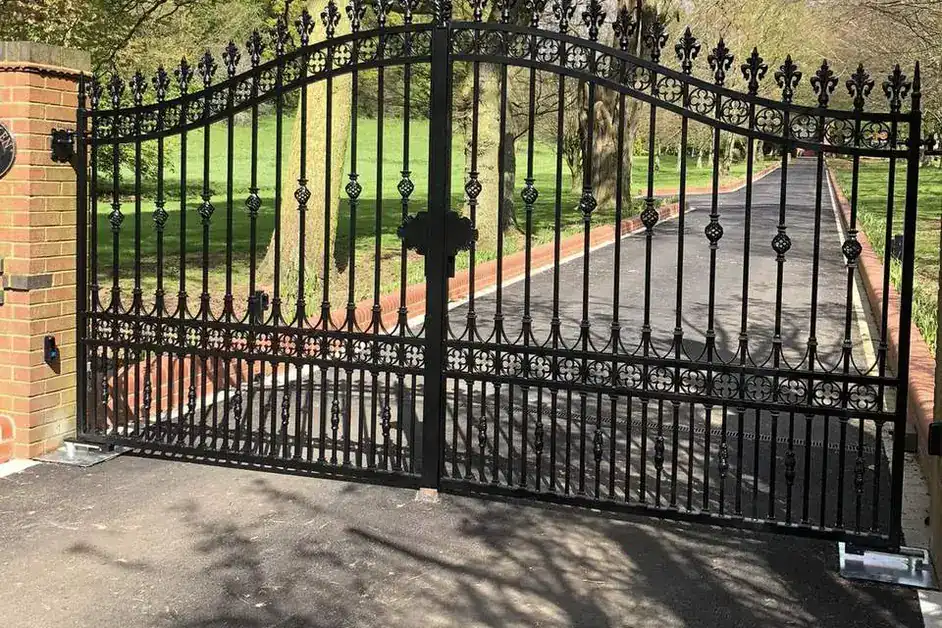 Ornate black iron gates across a tree-lined drive