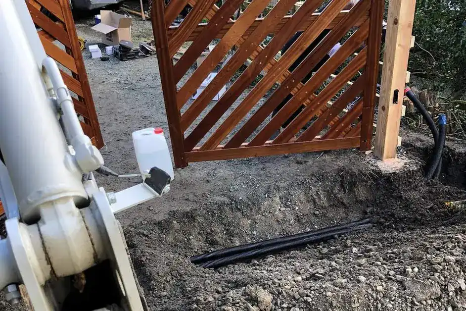 Timber gate on a new post, with a trench and ducting dug in front during installation