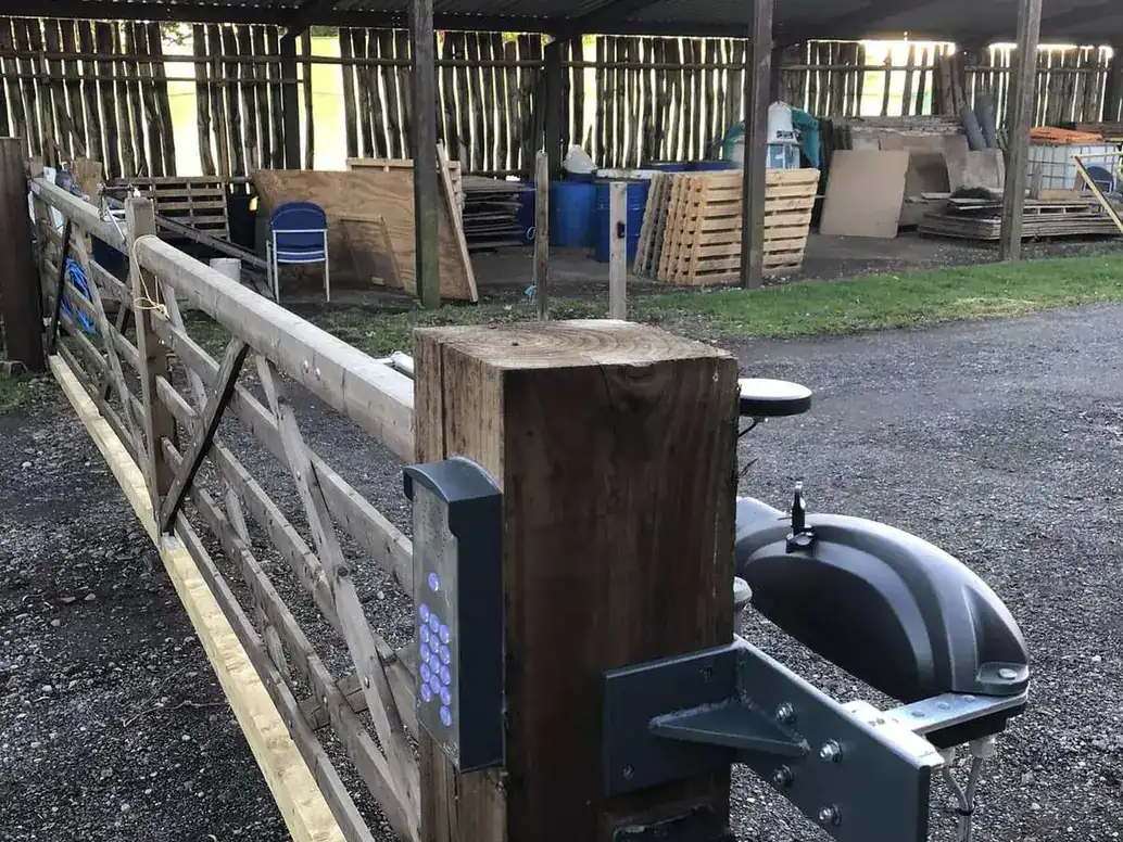 Keypad and ram arm on the post of a long timber gate at a stable yard