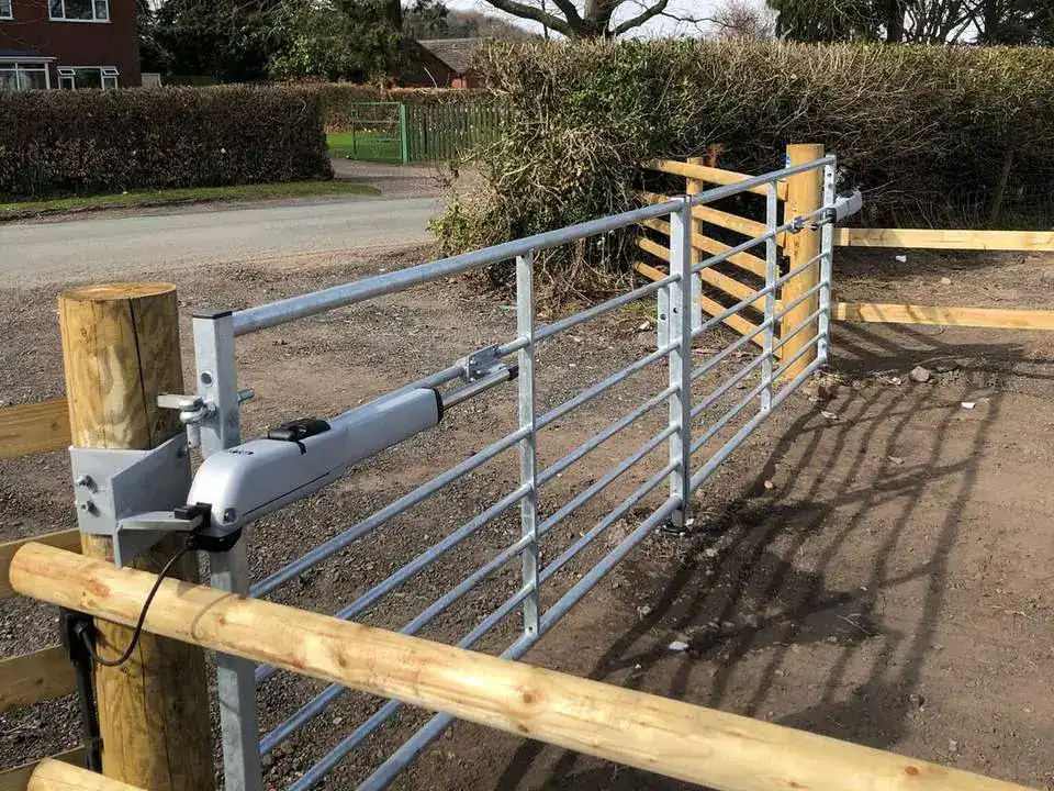 New timber posts and rails beside a galvanised field gate on a gravel drive