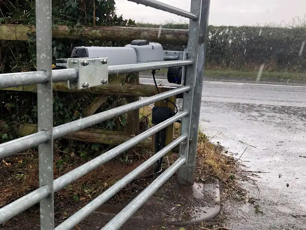 Ram arm fitted to a galvanised field gate beside a wet road
