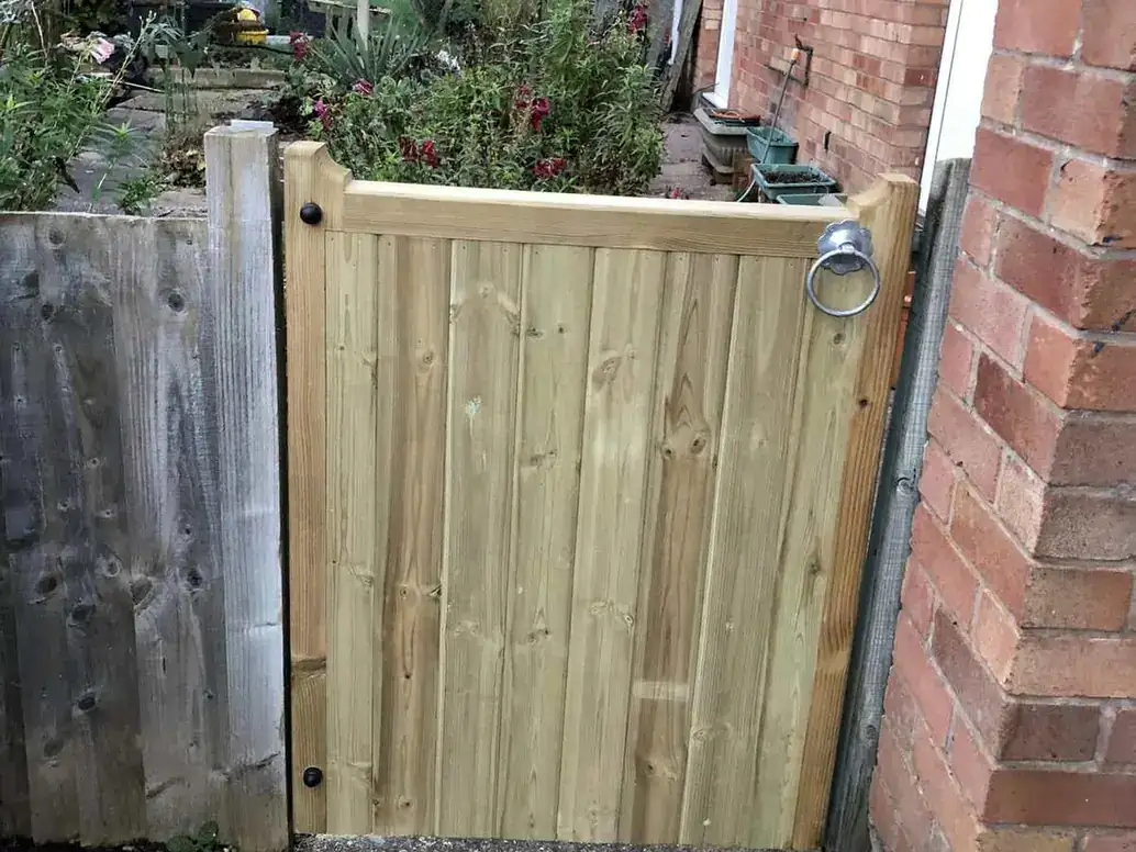 New timber side gate hung between a fence post and a brick wall