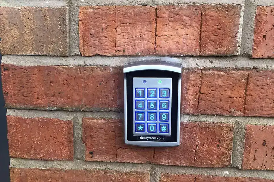 Illuminated code-entry keypad mounted on a red brick wall