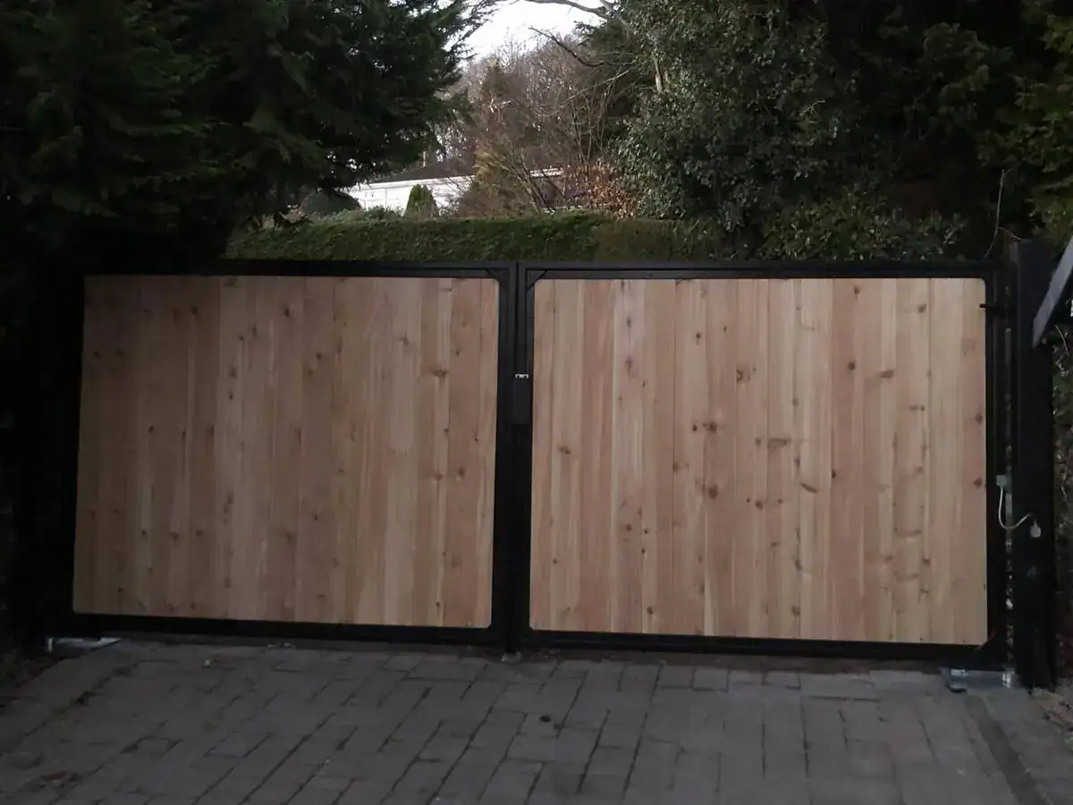 Cedar-clad gates in black steel frames across a block-paved drive