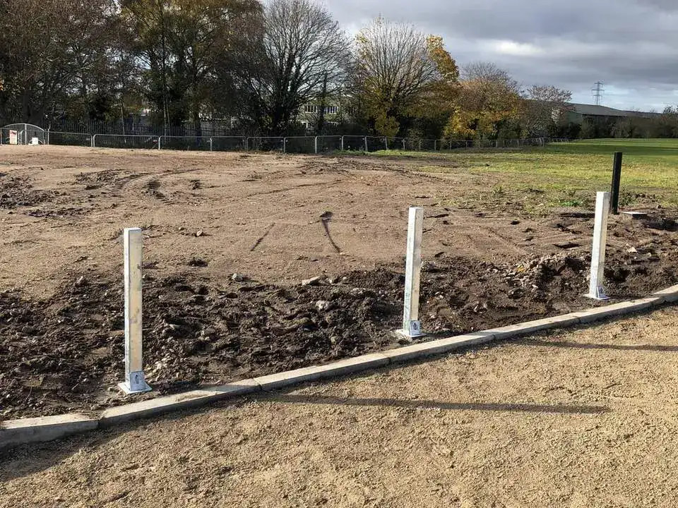 New steel posts set in freshly dug ground along the edge of a new drive