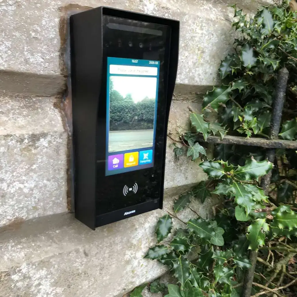 Video intercom with a colour touch screen on a stone wall beside ivy