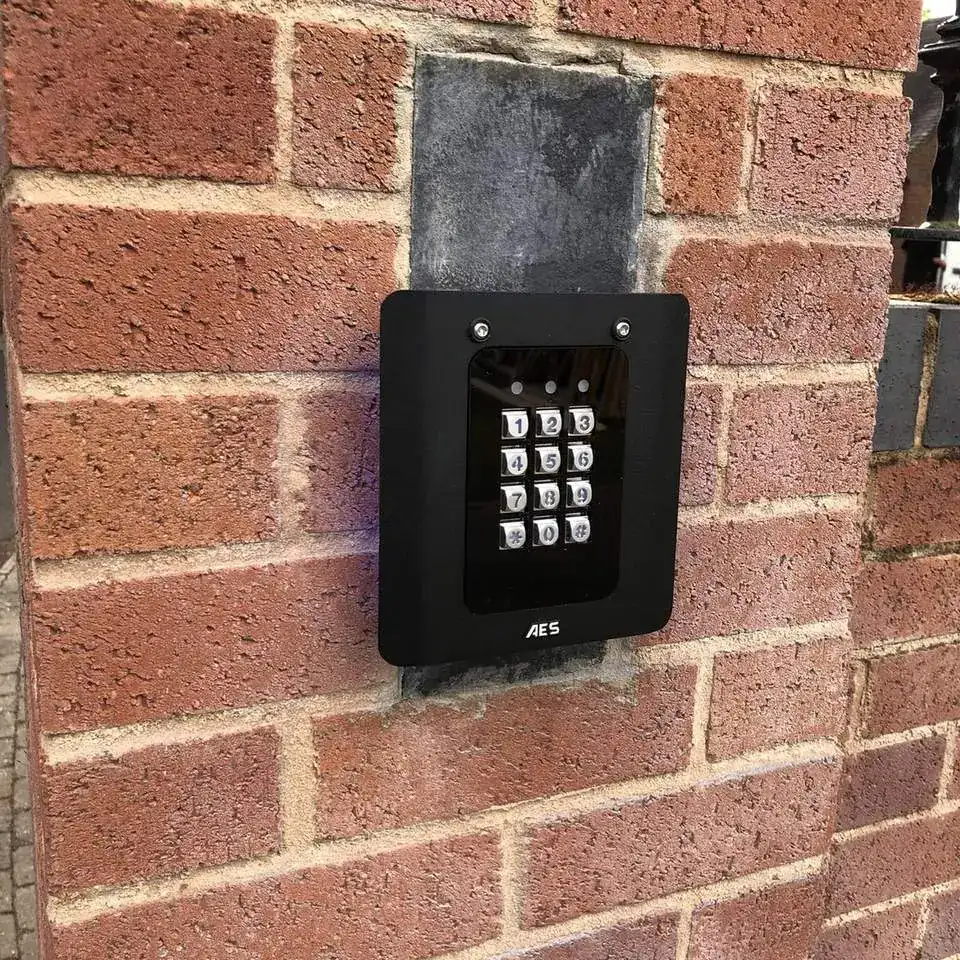 Black code-entry keypad set into a red brick pillar