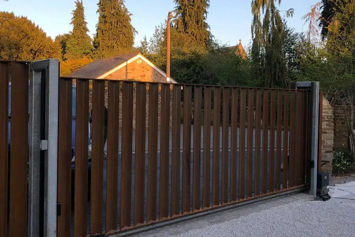 Timber-clad sliding gate on a new drive, trees behind