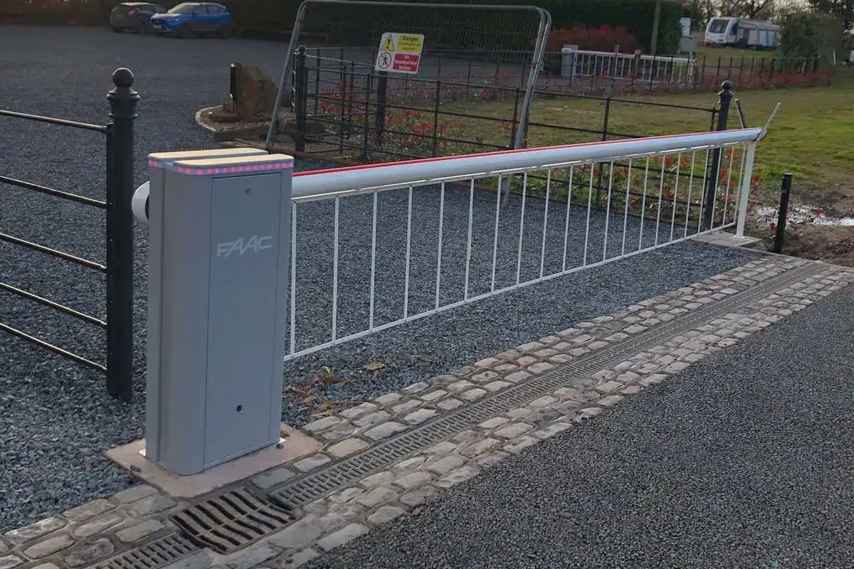White barrier arm with a hanging skirt across a new gravel entrance at sunset