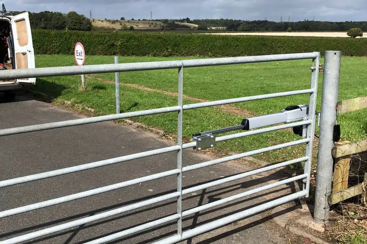 Galvanised field gate across a track beside a road