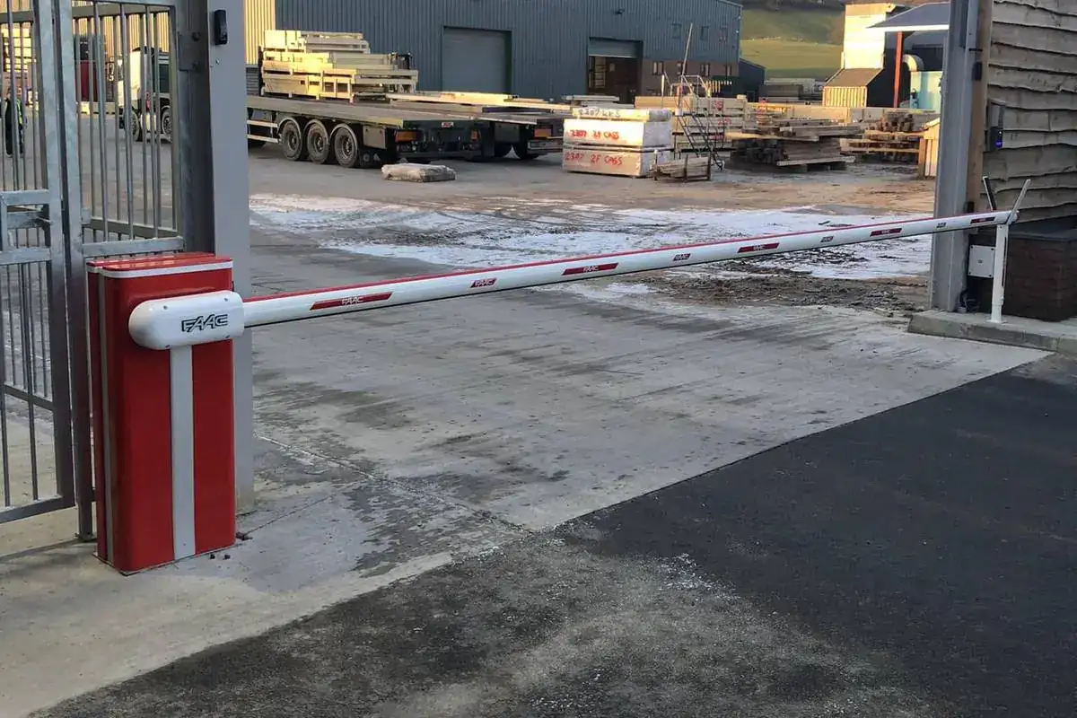 Red and white barrier across the yard entrance beside a timber-clad office building