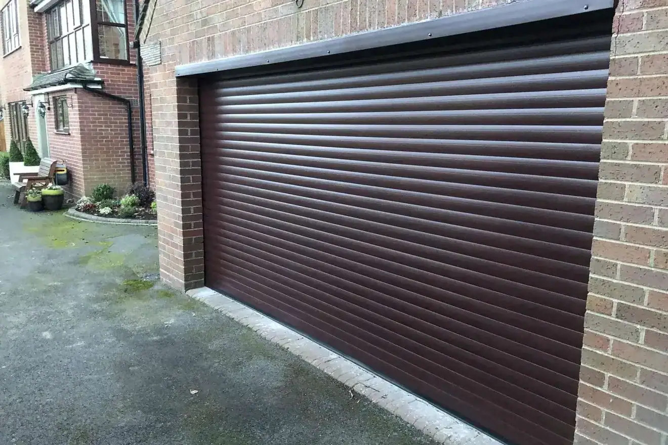 Rosewood roller garage door across a double garage beside a brick house
