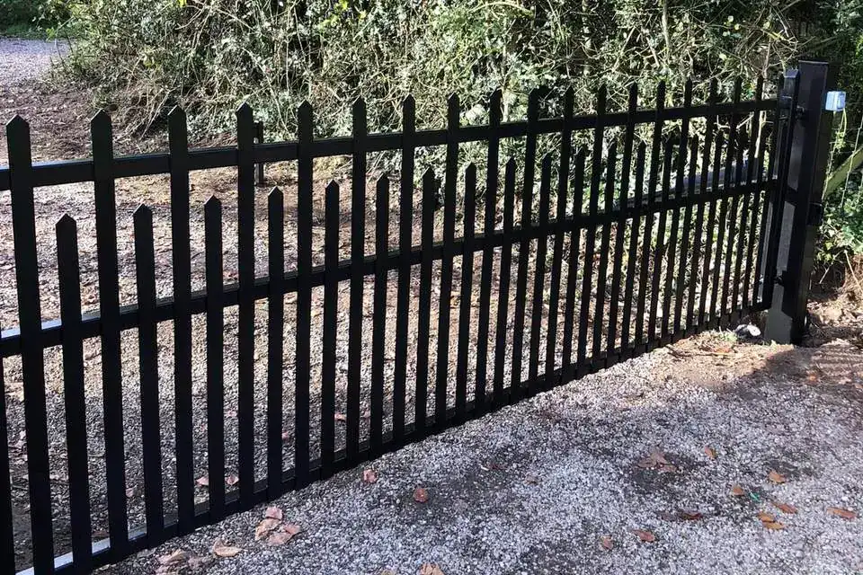 Black steel single-leaf gate with finials across a gravel track