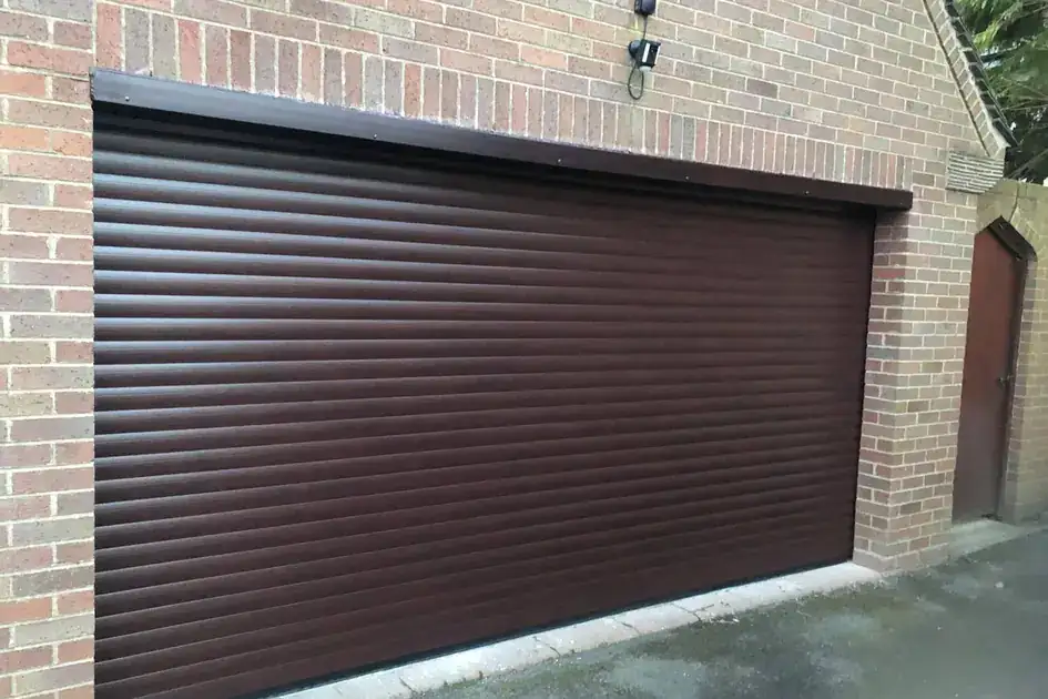 Brown roller garage door across a double garage in a brick wall