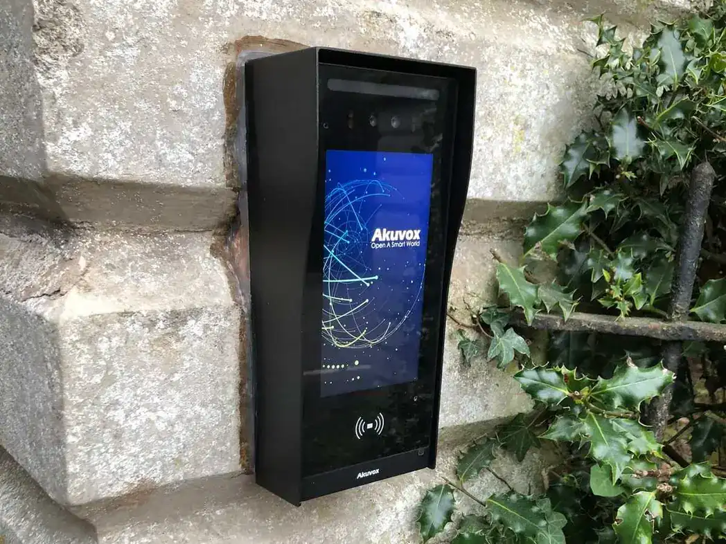 Video intercom mounted on a stone gate pillar beside ivy