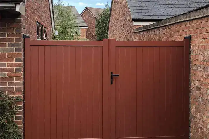 Lockable aluminium side gates in a red-brown finish between brick houses, Hadnall