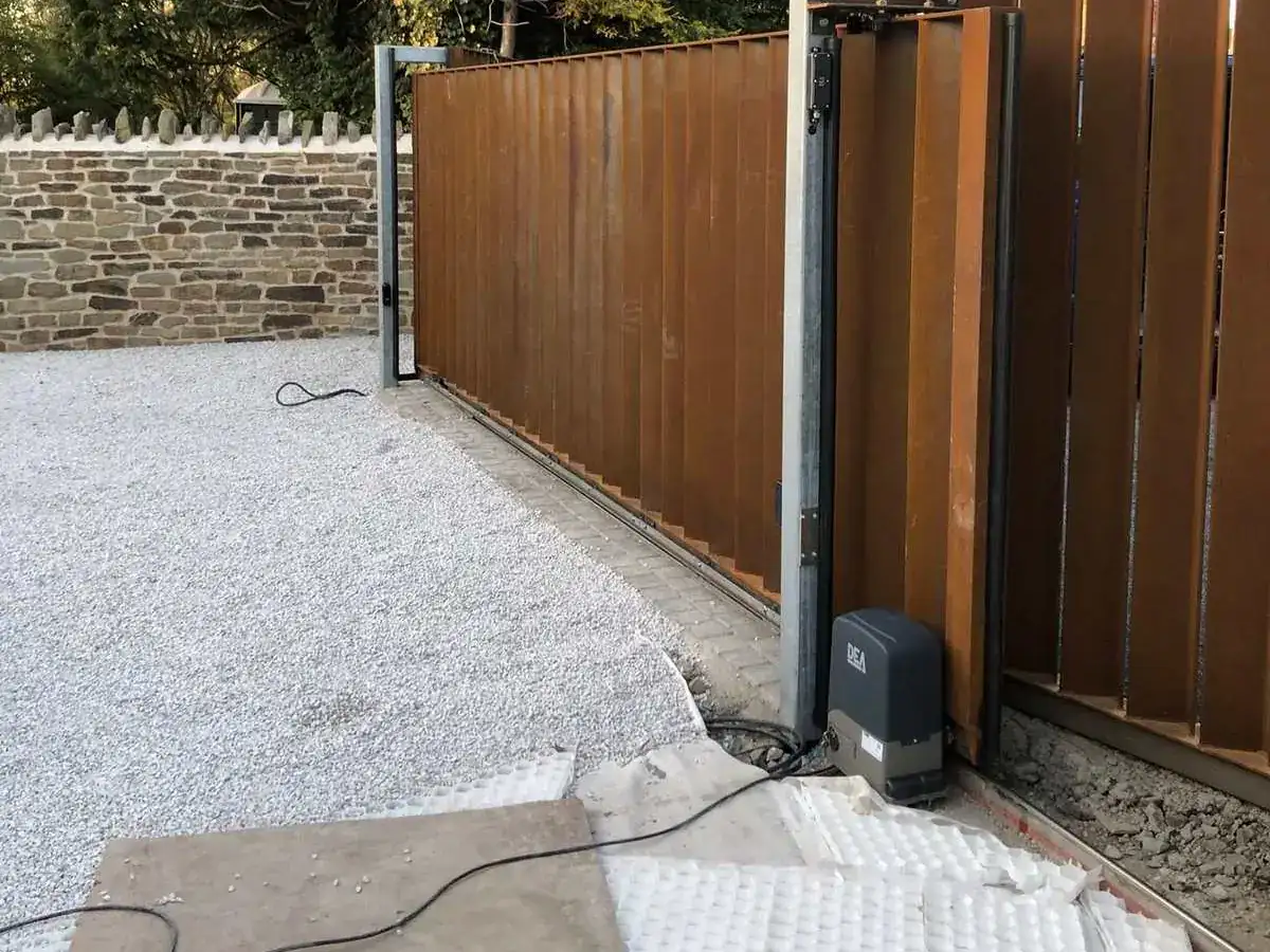 Sliding gate motor on its base at the end of a timber-clad sliding gate