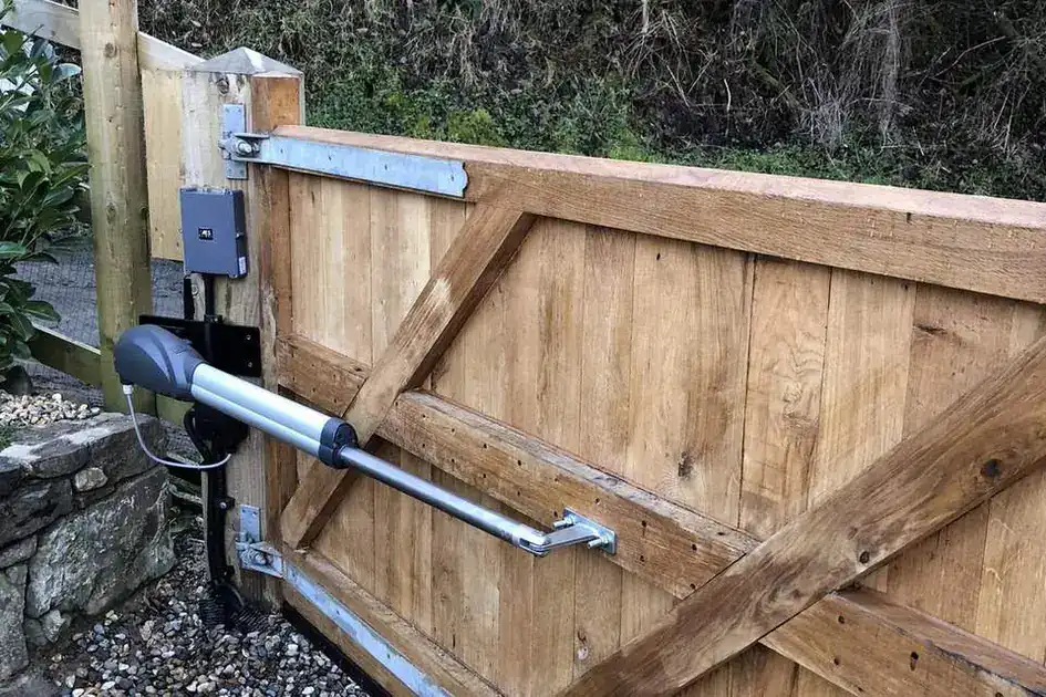 Ram arm operator fitted between a timber post and an oak driveway gate