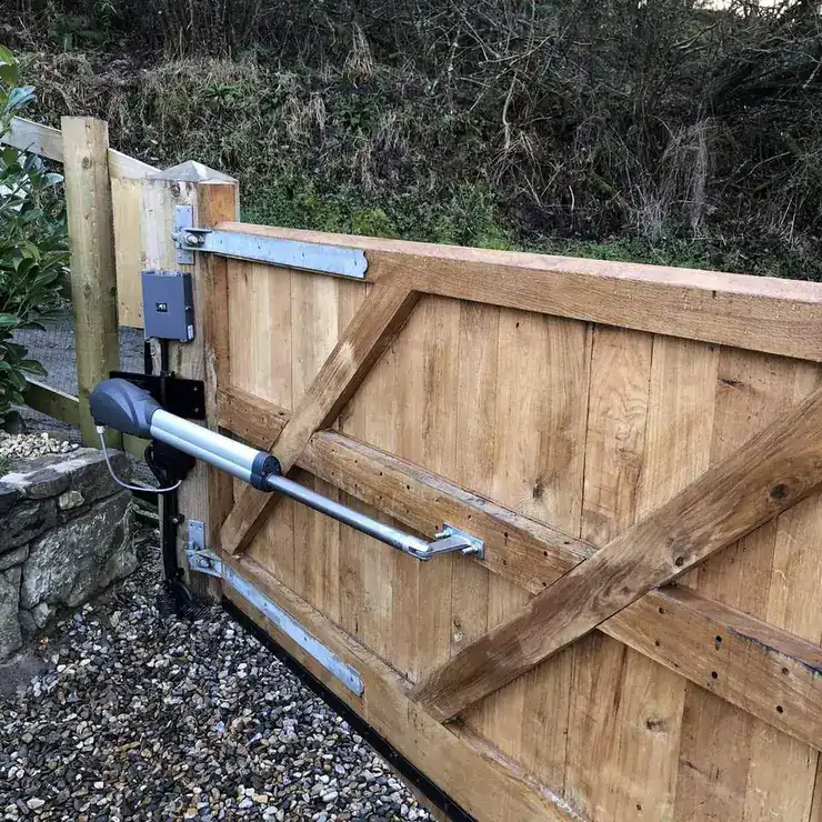 Ram arm operator fitted between a timber post and an oak driveway gate