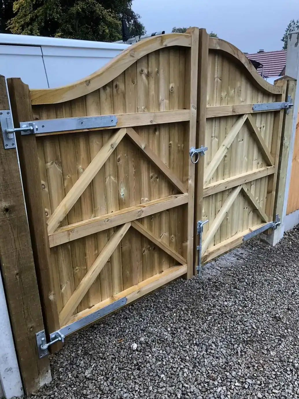 Pale timber double gates with an arched top and ledge-and-brace framing