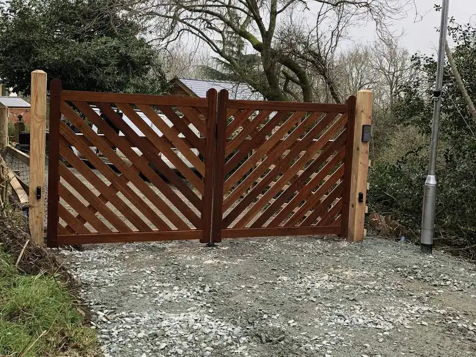 Red-brown timber gates with diagonal slats across a gravel drive