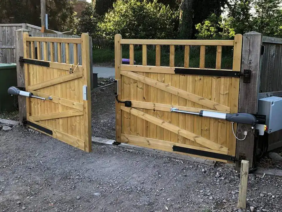 Pale timber gates with ram arms fitted, open onto a gravel drive